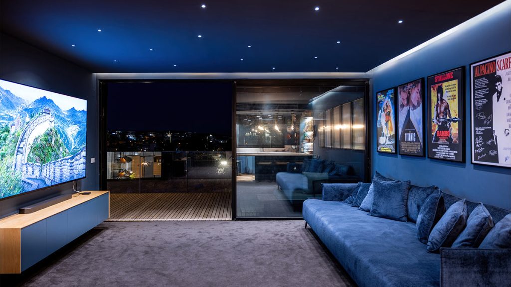 Nowoczesny salon z sufitowym projektorem wyświetlającym film na dużym ekranie z wygodnymi fotelami