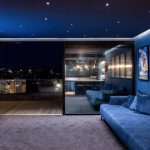 Rozdzielczość, jasność, kontrast - trzy parametry, które decydują o jakości obrazu w kinie domowym Nowoczesny salon z sufitowym projektorem wyświetlającym film na dużym ekranie z wygodnymi fotelami